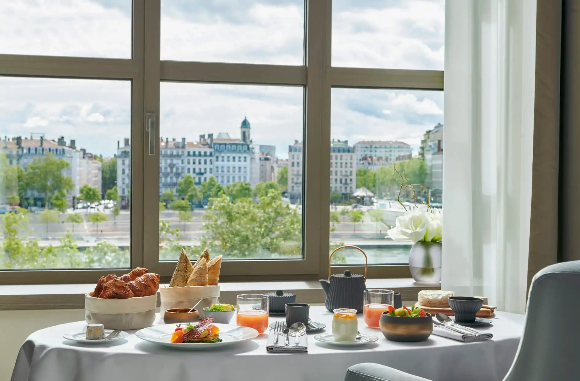 Table set with breakfast overlooking a river and city beyond